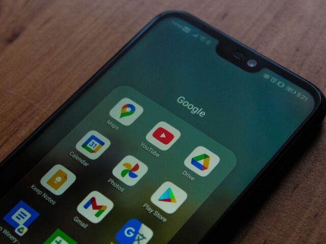 Close-up of a smartphone showing various Google apps on its screen.